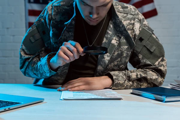 Handsome soldier holding magnifying glass while reading document in office — Stock Photo