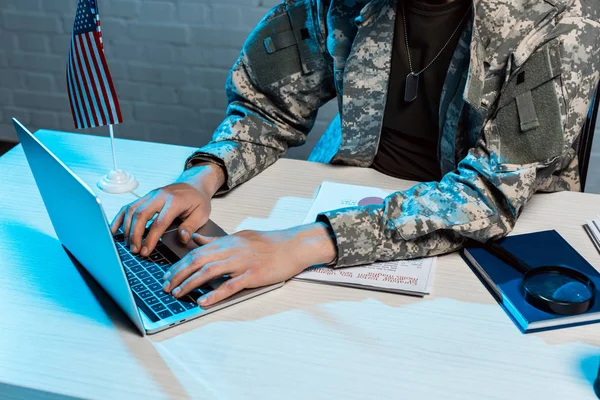 Обрезанный вид военнослужащего, печатающего на ноутбуке в офисе — стоковое фото