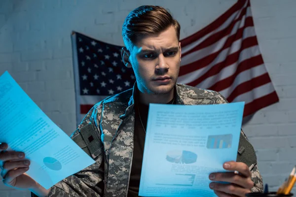 Handsome military man holding charts and graphs while sitting in office — Stock Photo