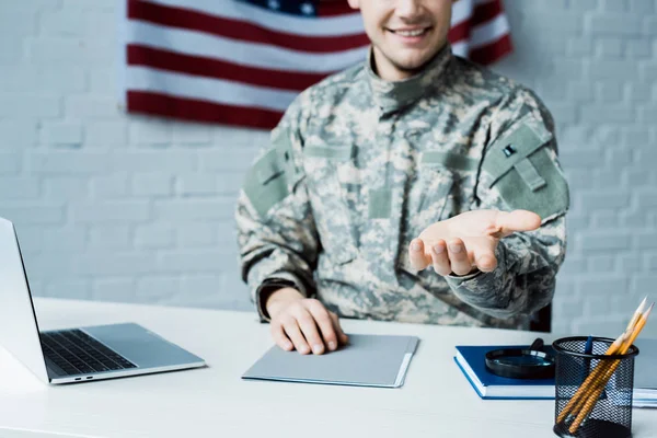 Vue recadrée du soldat heureux geste près de l'ordinateur portable dans le bureau — Photo de stock