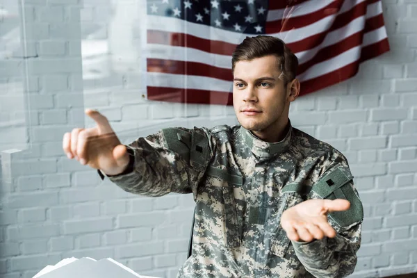 Handsome man in camouflage uniform pointing with finger in office — Stock Photo