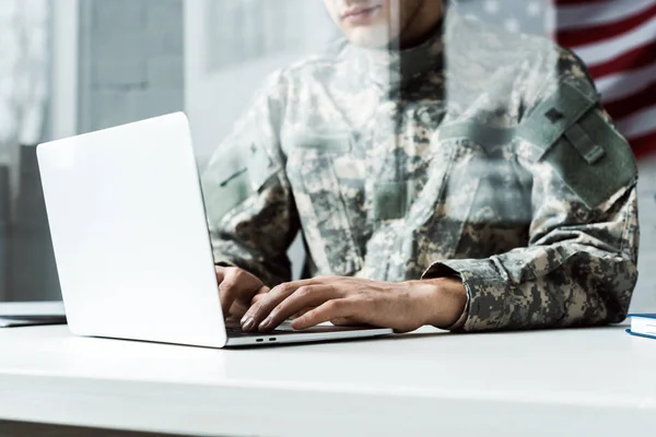 Vista recortada de soldado en uniforme de camuflaje utilizando el ordenador portátil - foto de stock