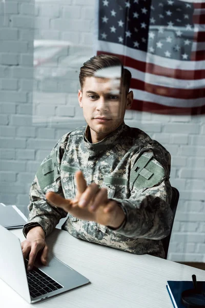 Enfoque selectivo del hombre guapo en camuflaje uniforme señalando con el dedo en la oficina - foto de stock