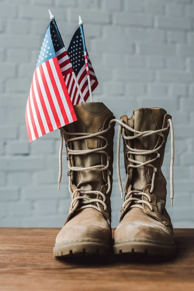 Военные сапоги и американские флаги со звездами и полосками на деревянном столе — стоковое фото