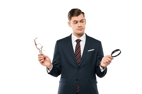 Homem de negócios bonito segurando óculos e lupa isolada em branco — Fotografia de Stock