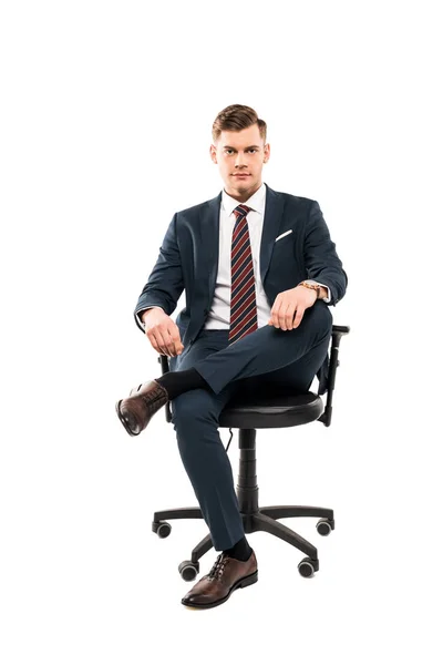 Confident businessman sitting on chair and looking at camera isolated on white — Stock Photo