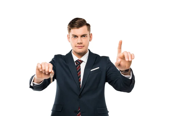 Schöner Mann im Anzug, der Schlüssel in der Hand hält und mit dem Finger auf Weiß zeigt — Stockfoto