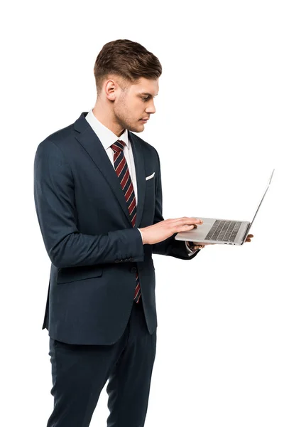Handsome businessman using laptop while standing isolated on white — Stock Photo