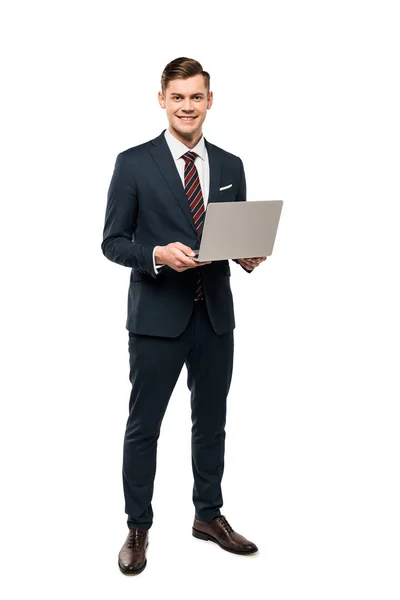 Homem feliz em terno segurando laptop e sorrindo enquanto estava isolado no branco — Fotografia de Stock