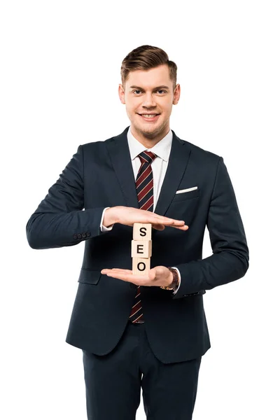 Happy businessman holding wooden cubes with seo lettering isolated on white — Stock Photo