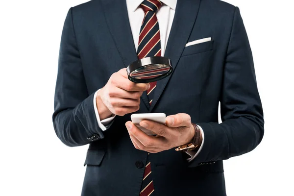 Vista recortada de hombre de negocios sosteniendo lupa cerca de teléfono inteligente aislado en blanco - foto de stock