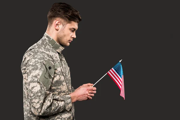 Homem triste em uniforme militar segurando bandeira americana isolado em cinza — Fotografia de Stock
