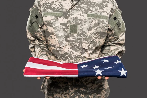 Обрезанный вид солдата в камуфляжной форме с американским флагом, изолированным на сером — стоковое фото