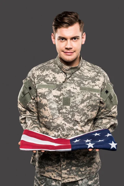 Homem feliz em uniforme militar segurando bandeira americana isolado em cinza — Fotografia de Stock