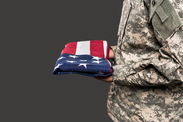 Cropped view of man in military uniform holding flag of america isolated on grey — Stock Photo