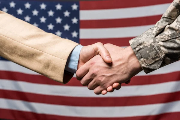 Enfoque selectivo hombres estrechando manos cerca de bandera americana - foto de stock