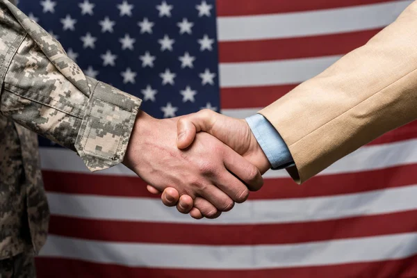 Selective focus military men shaking hands near american flag — Stock Photo