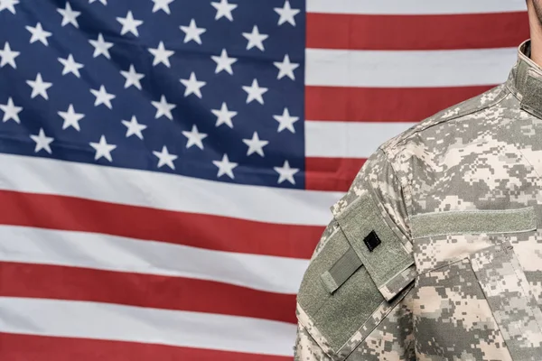 Vista cortada de soldado em uniforme militar perto da bandeira da América — Fotografia de Stock