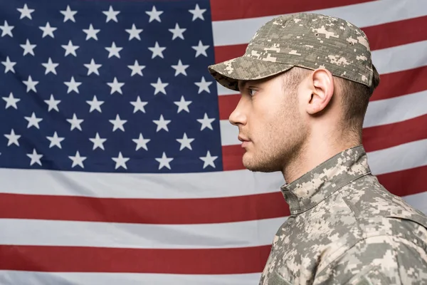 Homem bonito em uniforme militar e boné perto da bandeira da América — Fotografia de Stock