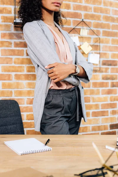 Vista recortada de afroamericana Casual mujer de negocios con brazos cruzados en la oficina loft - foto de stock