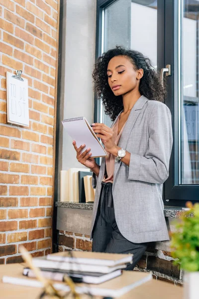 African american Casual businesswoman writing in notepad in loft office — Stock Photo