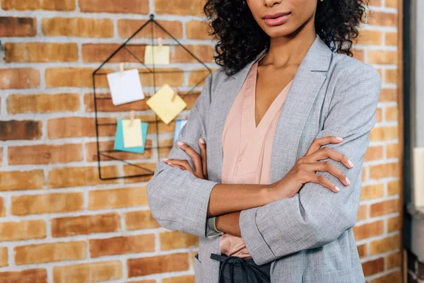 Обрізаний вид афроамериканської бізнес-леді з схрещеними руками в офісі лофт — стокове фото