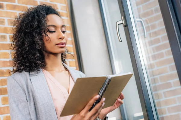 Bella donna d'affari africana americana casual in possesso di notebook in ufficio loft — Foto stock