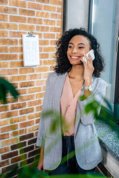 Enfoque selectivo de sonriente afroamericana Casual mujer de negocios hablando en el teléfono inteligente - foto de stock