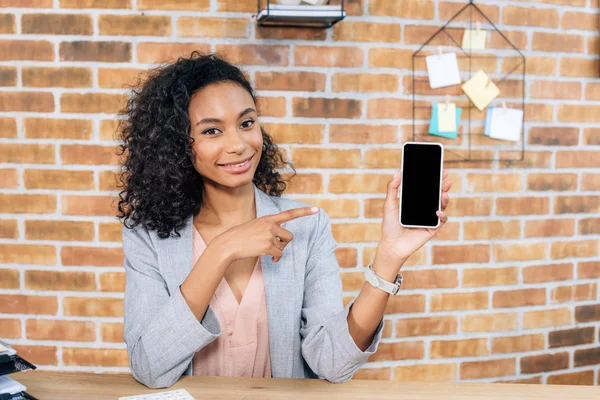 Afroamericano Casual donna d'affari che punta con il dito allo smartphone con schermo bianco in ufficio loft — Foto stock