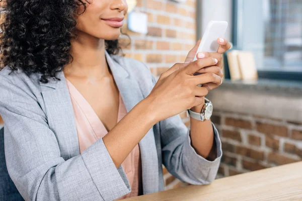Cropped view of african american Casual businesswoman using smartphone in loft office — Stock Photo