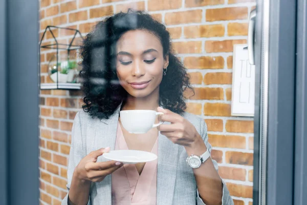 Africano americano Casual empresária com xícara de café atrás da janela — Fotografia de Stock