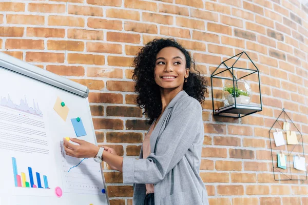 Smiling african american Casual businesswoman near flipchart during Presentation in loft office — Stock Photo