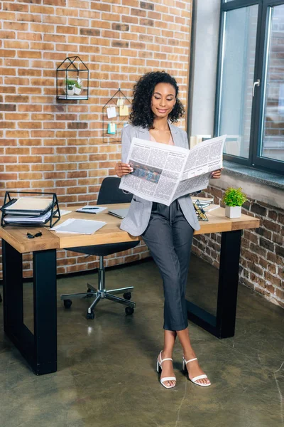 Hermosa mujer de negocios casual leyendo periódico de negocios en la oficina loft - foto de stock