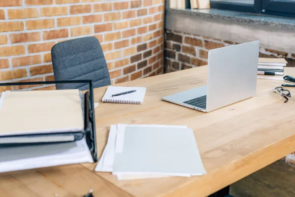 Wooden desk with laptop and documents in loft office — Stock Photo