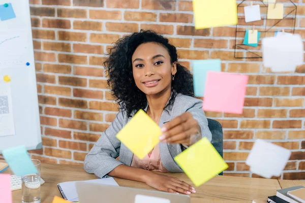 Schöne afrikanisch-amerikanische Gelegenheitsunternehmerin, die im Büro klebrige Zettel an Glasfenster klebt — Stockfoto