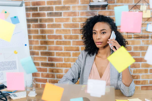 Selective focus of african american Casual businesswoman talking on smartphone in loft office — Stock Photo