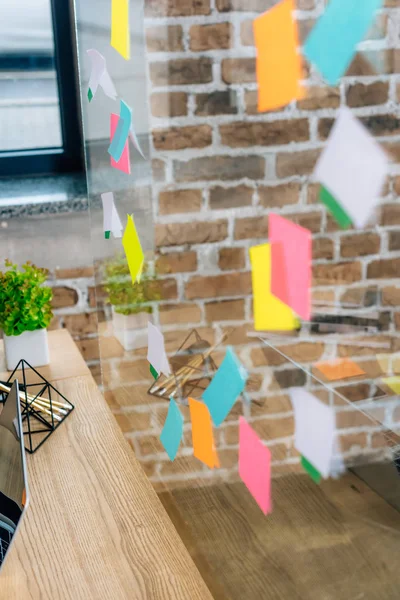 Selective focus of colorful Sticky Notes on glass window in loft office — Stock Photo