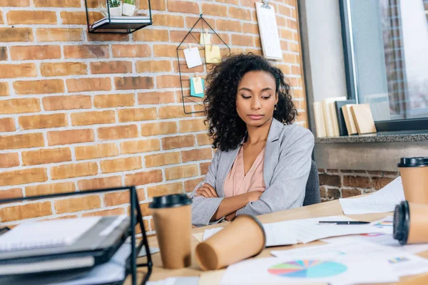 Афроамериканська випадкова бізнес-леді за столом з кавою, щоб піти чашки і папери в офісі — стокове фото
