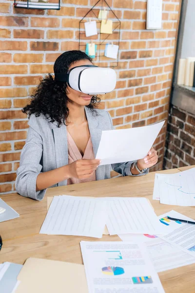 Африканский американец Случайная деловая женщина в гарнитуре виртуальной реальности в офисе стол с документами — стоковое фото