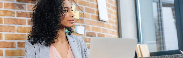 Panoramic shot of beautiful Casual african american businesswoman using laptop in loft office — Stock Photo