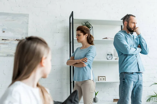 Selective focus of offended woman standing with crossed arms near husband at home — Stock Photo