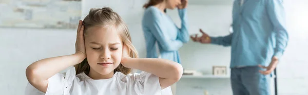 Panoramic shot of kid with closed eyes covering ears near parents at home — Stock Photo