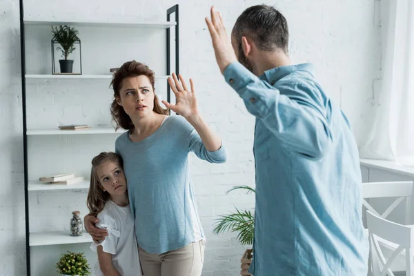 Messa a fuoco selettiva di madre spaventata gesticolando mentre guardando il marito arrabbiato a casa — Foto stock