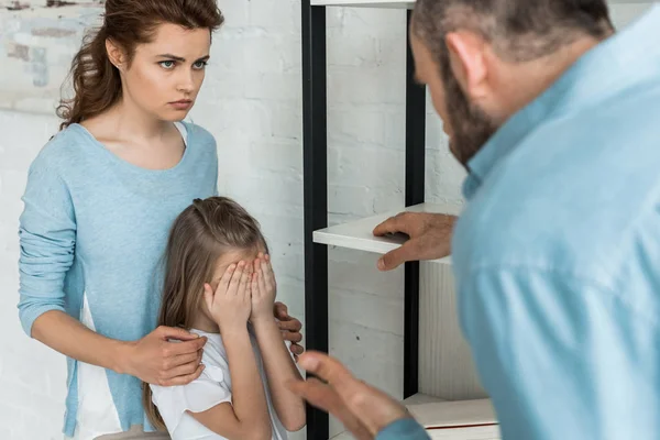 Enfoque selectivo del niño cubriendo la cara cerca de la madre y el padre en casa - foto de stock