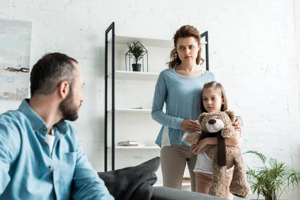 Selective focus of kid holding teddy bear near mother while looking at father — Stock Photo