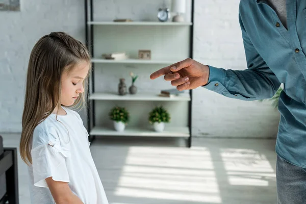 Cropped view of man pointing with finger at adorable daughter at home — Stock Photo