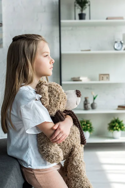 Niedliches Kind steht und hält Teddybär zu Hause — Stockfoto