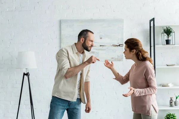 Bärtiger Mann steht und zeigt mit dem Finger auf attraktive Frau — Stockfoto