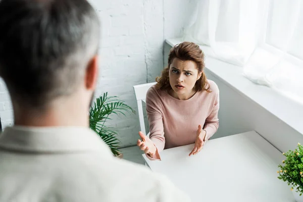 Selective focus of offended woman looking at man and gesturing at home — Stock Photo