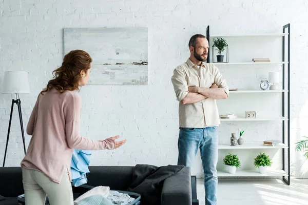 Brunette woman gesturing while looking at man standing with crossed arms — Stock Photo